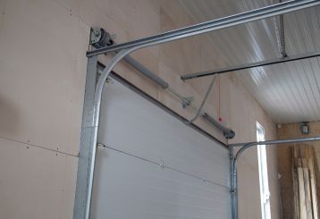 Interior view of a newly installed sectional garage door with metal tracks and opener system in a Blaine, Minnesota garage.