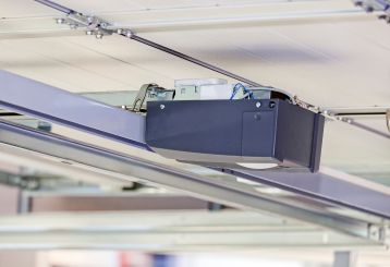Close-up of a modern garage door opener motor mounted on the ceiling track in a residential garage in Blaine, Minnesota.