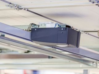 Close-up of a modern garage door opener motor mounted on the ceiling track in a residential garage in Blaine, Minnesota.