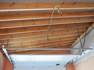 Garage Door Spring and Rail Installation in Blaine MN Garage ceiling with visible wooden beams, a newly installed garage door rail, and spring assembly in Blaine, Minnesota.