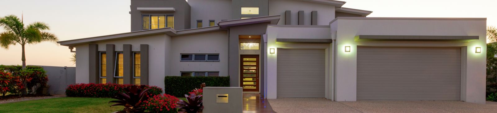 Contemporary Blaine, MN home at dusk with two large modern garage doors and stylish exterior lighting.