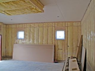 Garage Door Weatherproofing and Insulation in Blaine MN Garage interior with new insulation, drywall sheets, and plastic vapor barrier installed on walls and ceiling in Blaine, Minnesota.